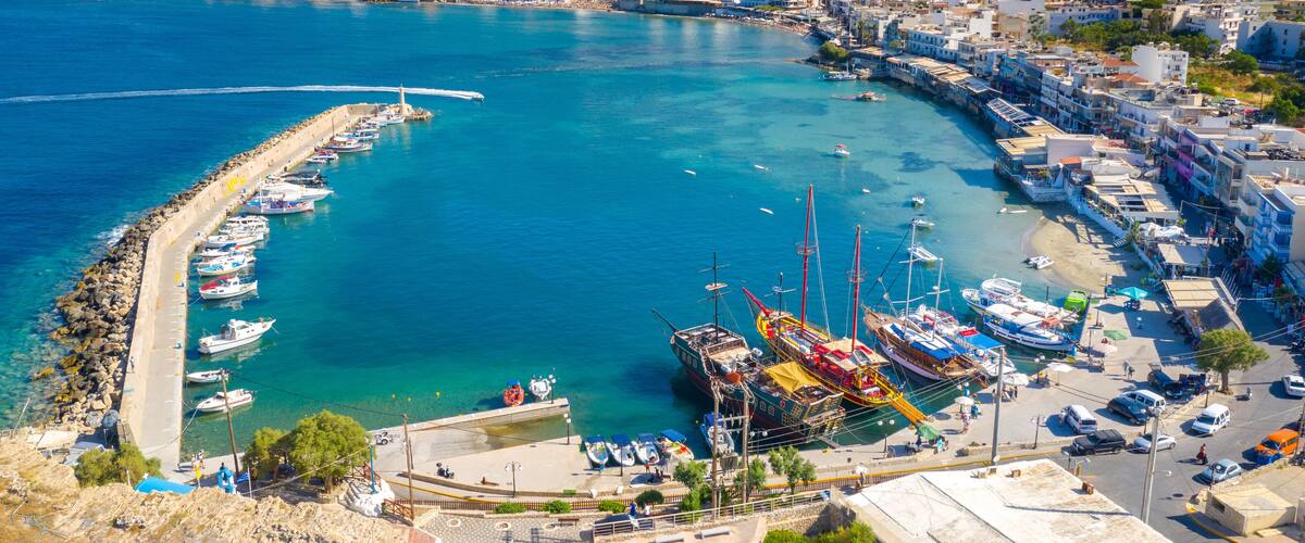 A coastal town with a marina, boats, and buildings along the waterfront.