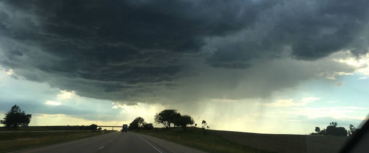 A road with a dark stormy sky overhead.