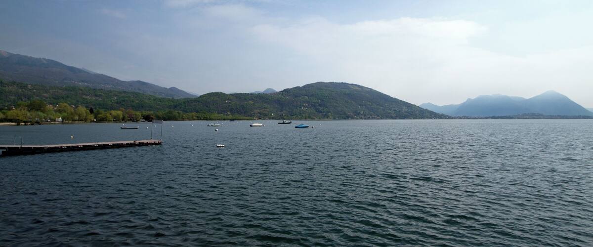 A calm lake with boats, a dock, and mountains in the background.