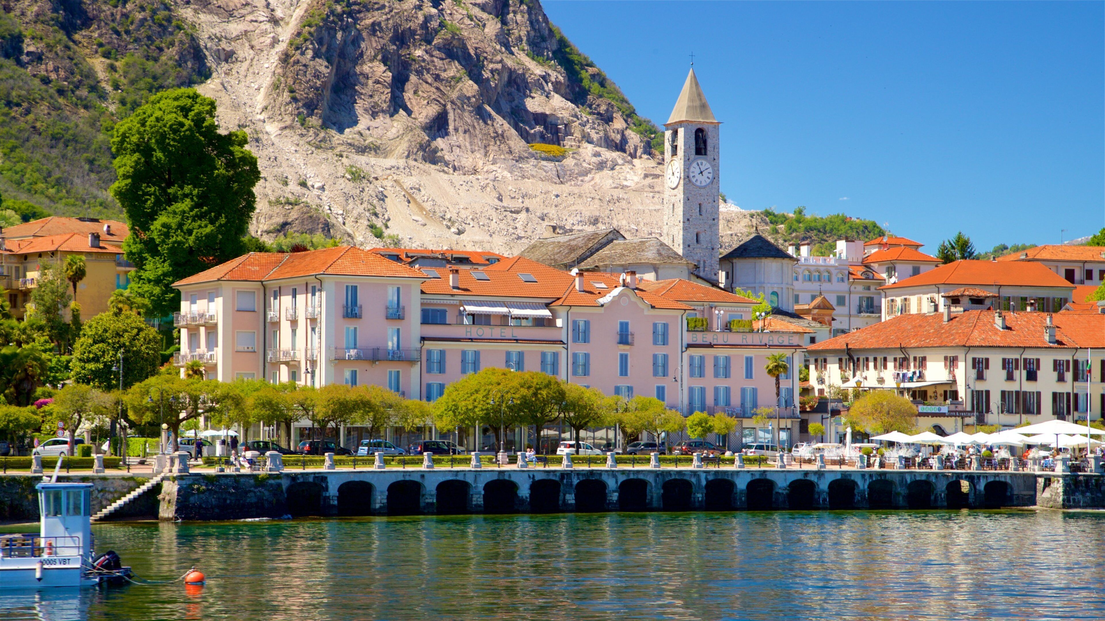 A coastal town with a prominent church tower, a bridge, and a hotel named "Beau Rivage."