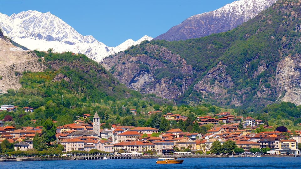A coastal town with red-roofed buildings, a clock tower, and snow-capped mountains in the background.