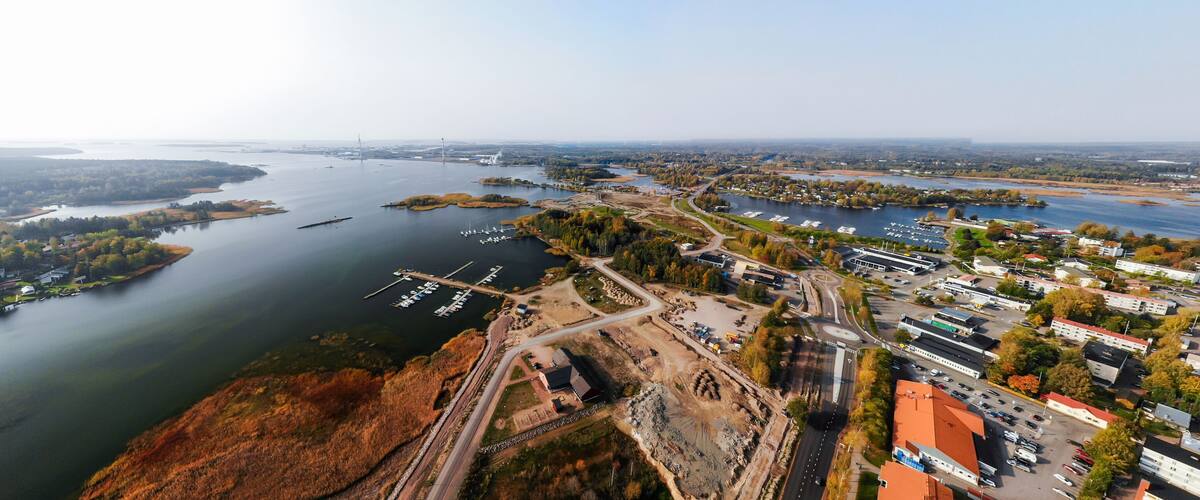 An aerial view of a river with a marina, a bridge, and surrounding urban and natural landscapes.