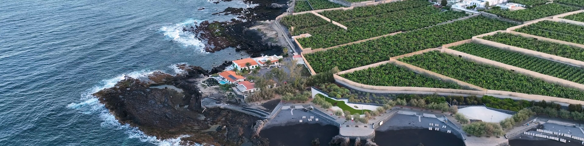 A coastal landscape with rocky cliffs, a beach, and agricultural fields.