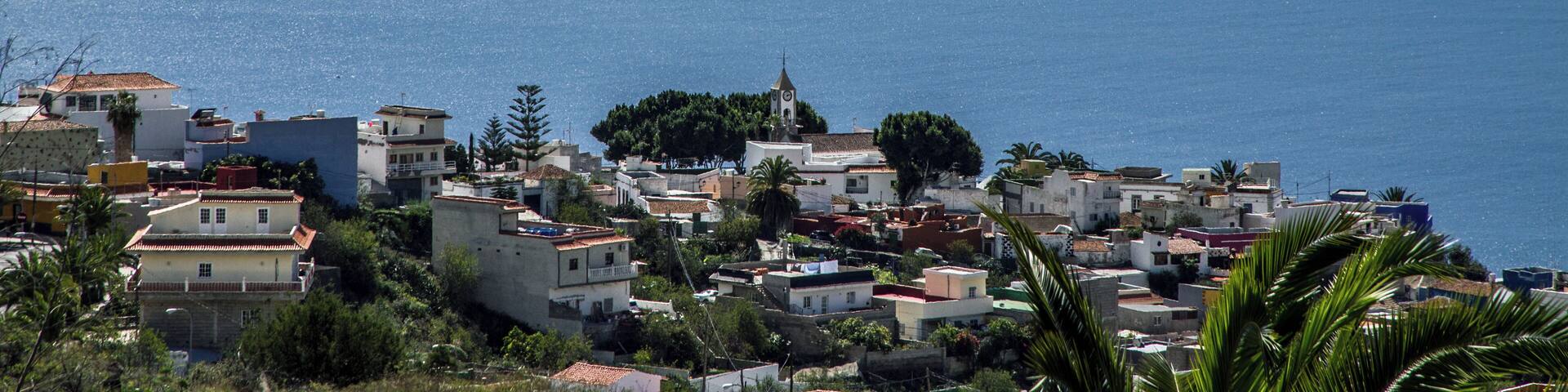 A coastal town with buildings and a church, overlooking the sea.