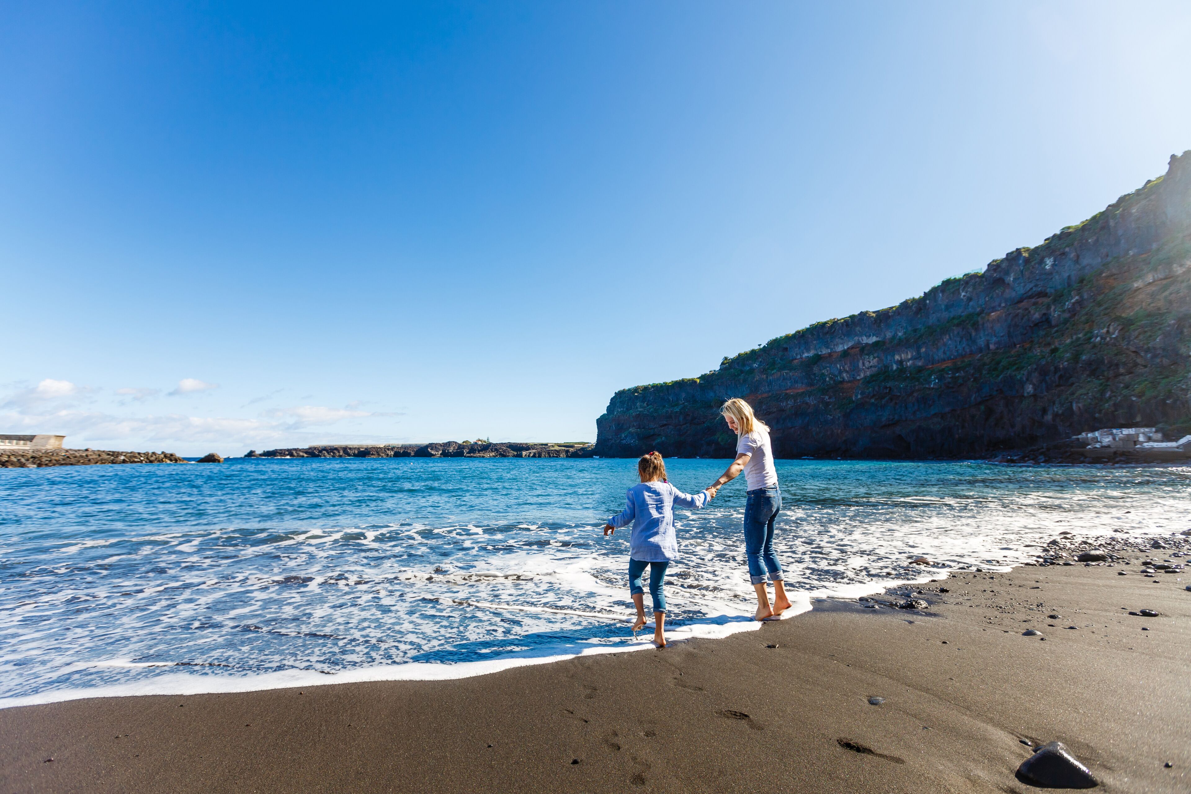 Una playa con un acantilado rocoso y un mar tranquilo.
