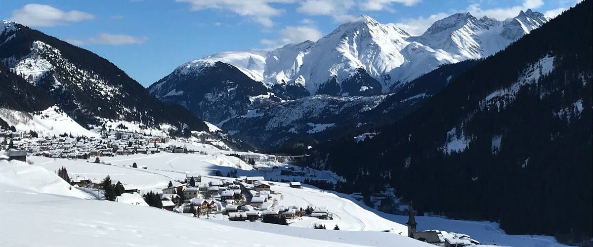 A snow-covered mountain range with a village nestled in the valley.