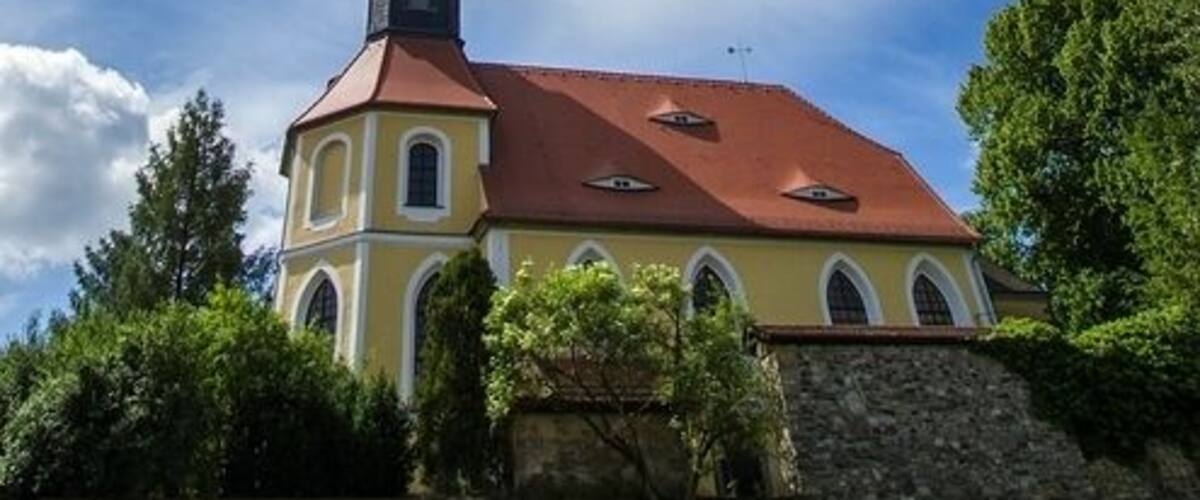 A church with a red roof and a clock tower under a partly cloudy sky.