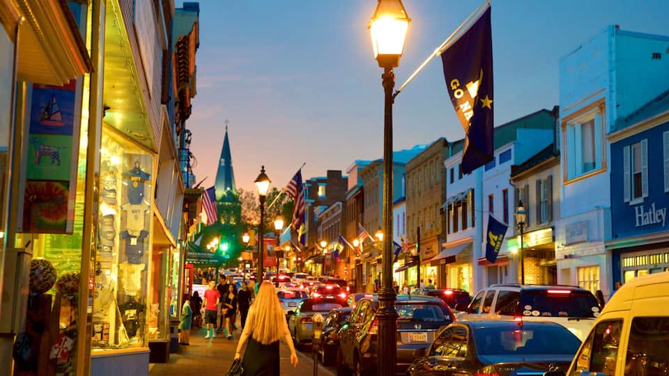 A busy street with cars, pedestrians, and illuminated buildings at dusk.