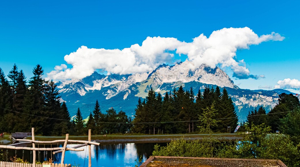 Alpine summer view with reflections in a lake and Mount Wilder Kaiser covered in clouds seen from Mount Harschbichl, Sankt Johann in Tirol, Kitzbuehel, Tyrol, Austria