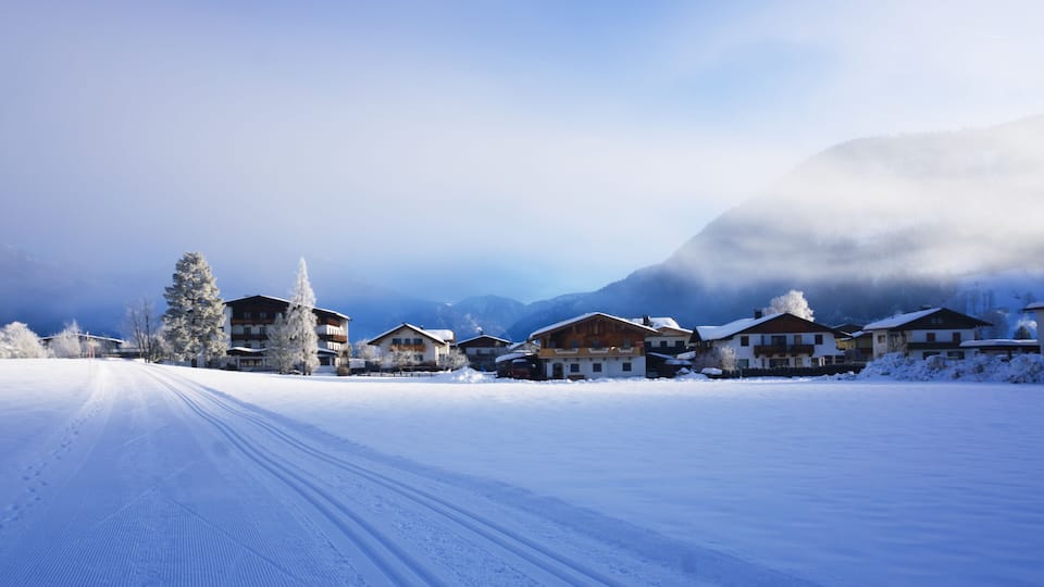 A snow-covered village with buildings and a mountain in the background.