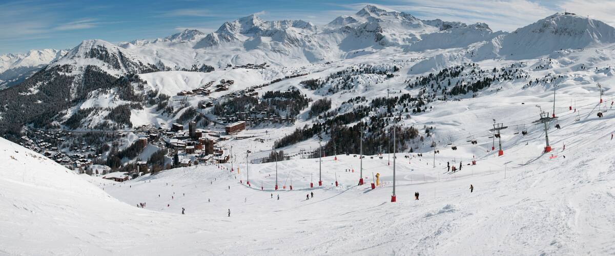 A snow-covered mountain landscape with ski slopes, ski lifts, and a town nestled among the peaks.