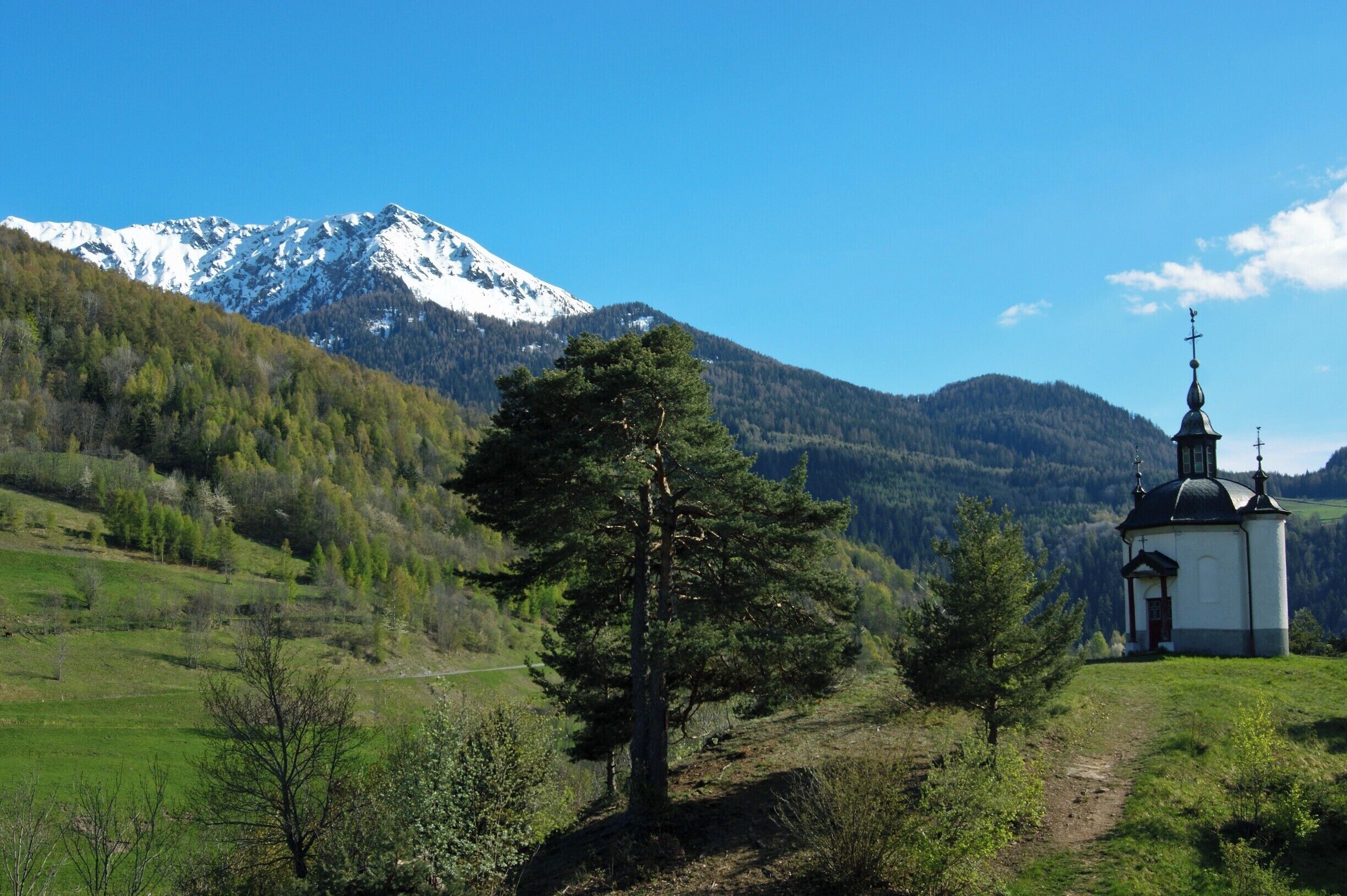 A church in a mountainous area with snow-capped peaks in the background.
