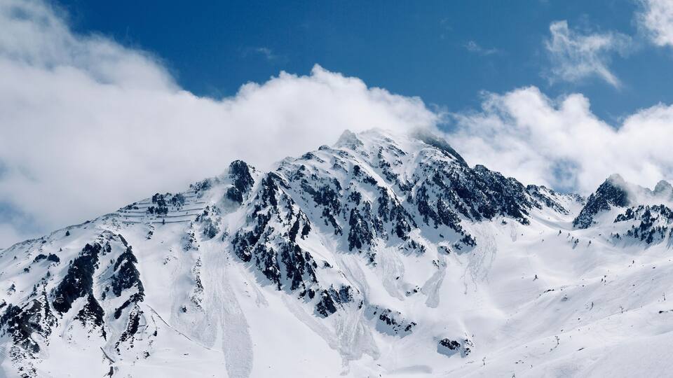 A snow-covered mountain range with sharp peaks and a clear blue sky.