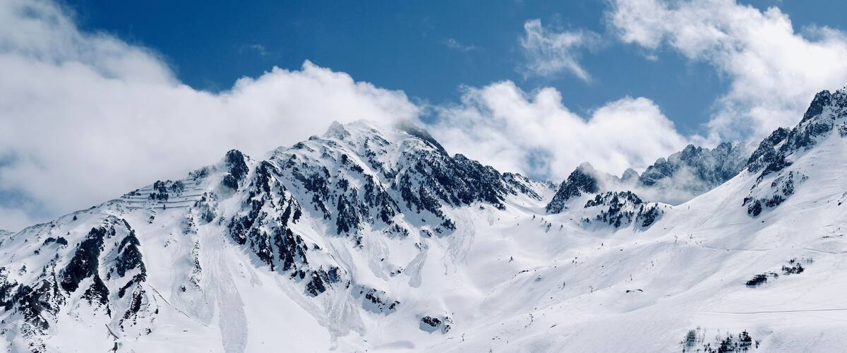 A snow-covered mountain range with sharp peaks and a clear blue sky.