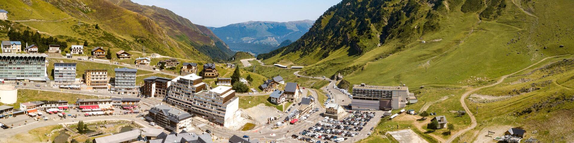A mountainous town with buildings, roads, and a parking lot.