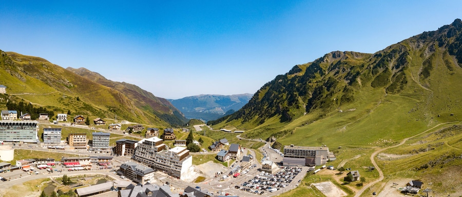 Uma cidade montanhosa com edifícios, estradas e um estacionamento.