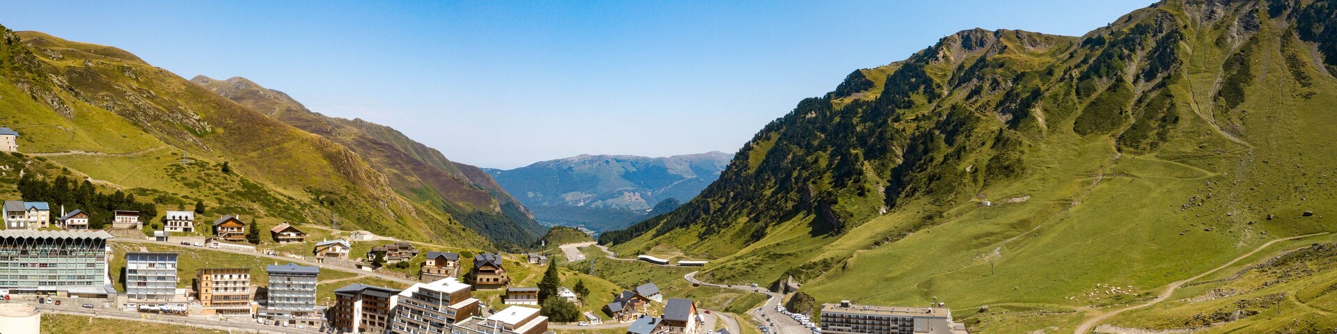 Uma cidade montanhosa com edifícios, estradas e um estacionamento.