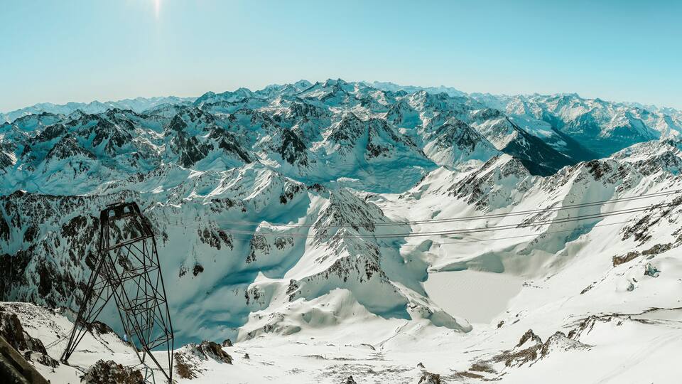 A snow-covered mountain range with a visible power line structure.