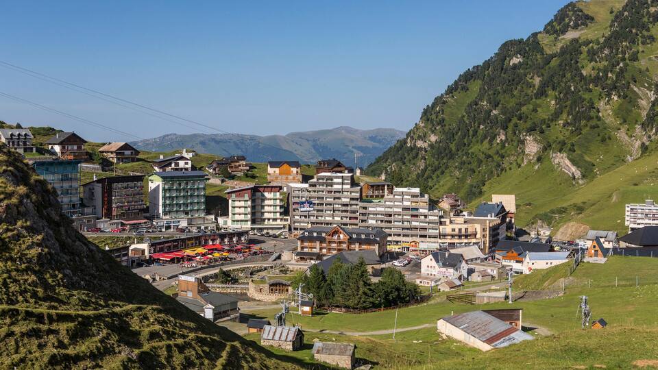 A mountainous town with buildings, a ski lift, and a clear blue sky.