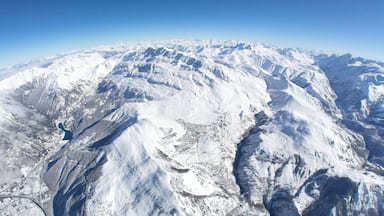 A snow-covered mountain range with a glacier and a small town at the base.