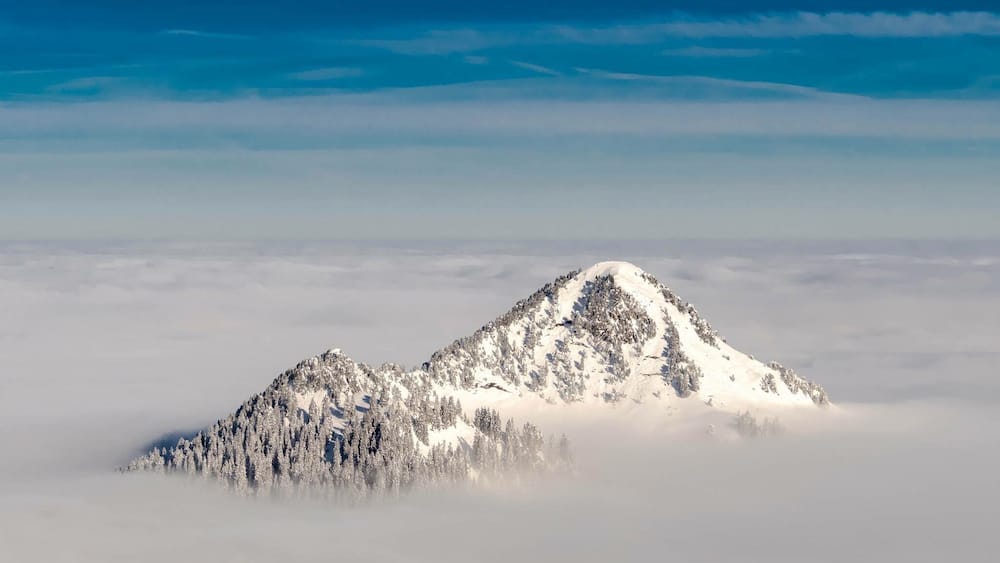 A snow-covered mountain peak surrounded by clouds.