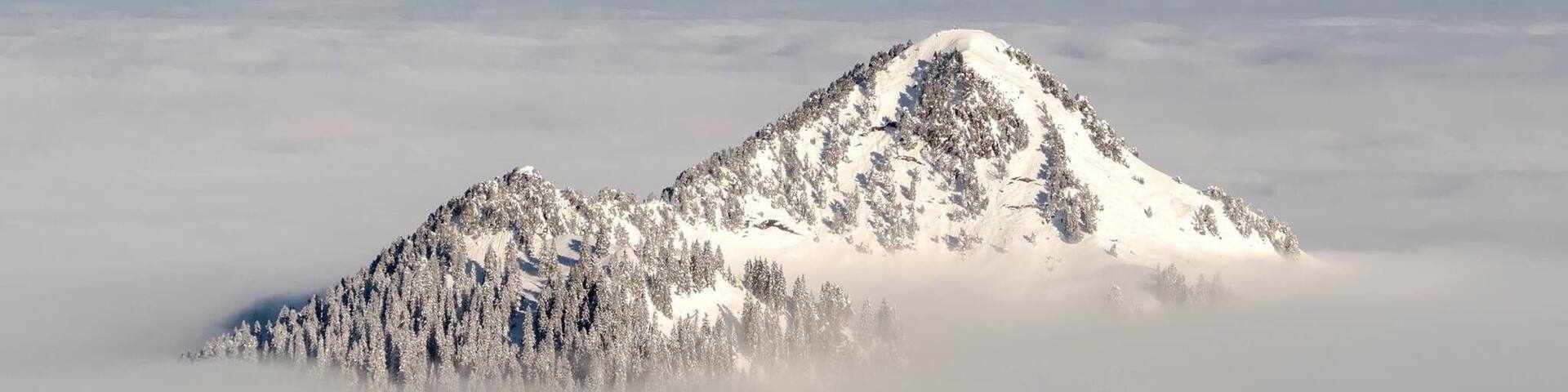 A snow-covered mountain peak surrounded by clouds.