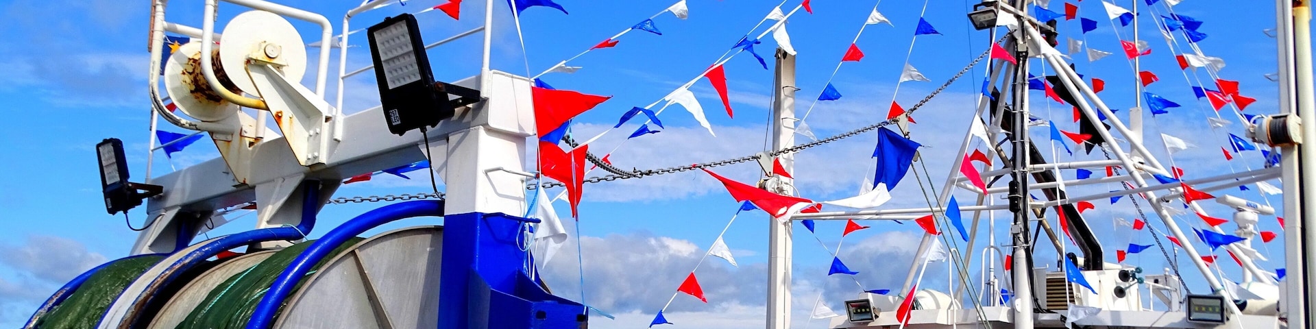Um barco decorado com várias bandeiras, incluindo as bandeiras do Canadá e da França, e festas decorativas em vermelho, branco e azul.