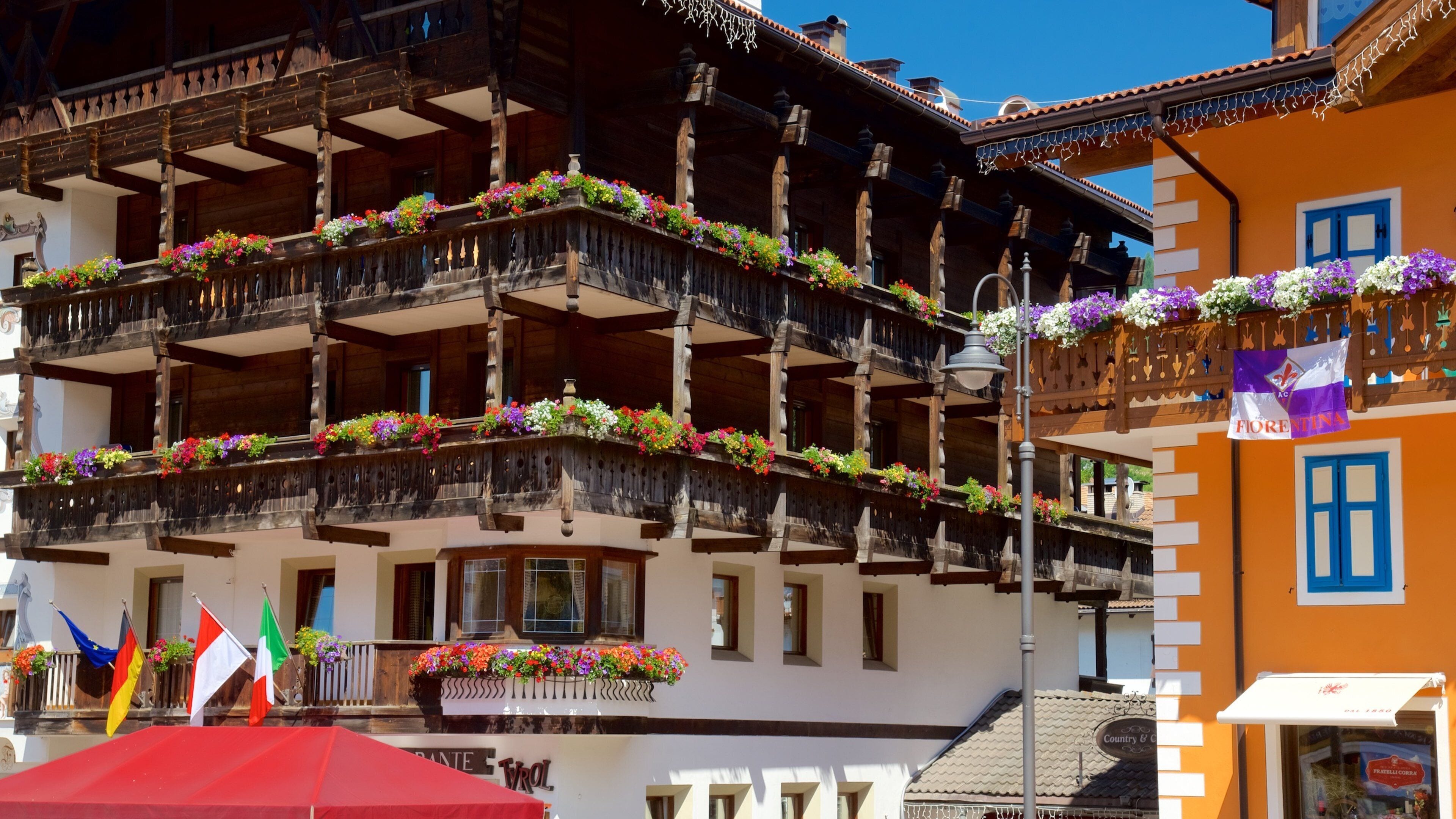 A traditional wooden building with balconies adorned with colorful flowers, flags, and a sign reading "Country & Co."