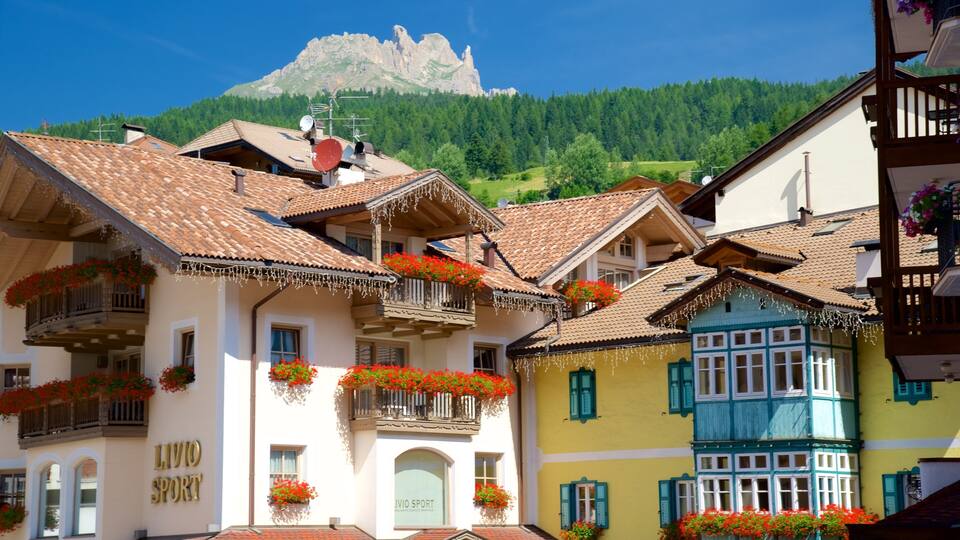 A traditional European village with colorful buildings, balconies with flower boxes, and a mountain in the background.
