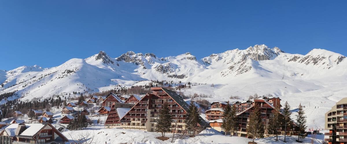 A snow-covered mountain village with chalet-style buildings and a ski slope.
