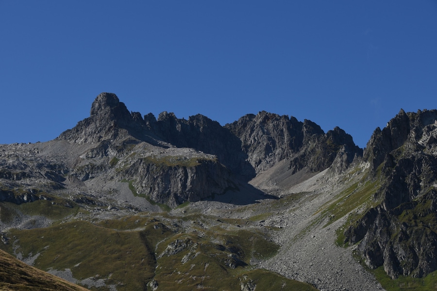 Rugged mountain peaks with sparse vegetation under a clear blue sky.