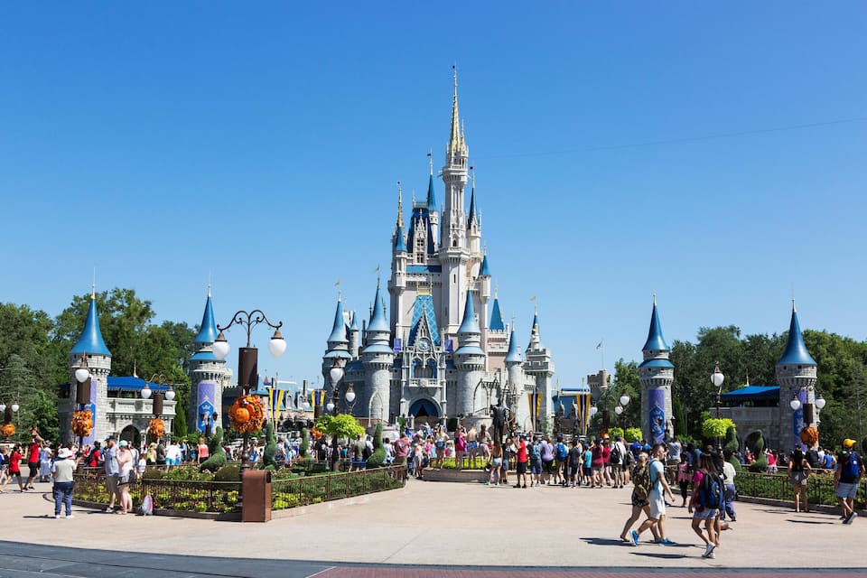 A large castle with multiple spires and turrets, surrounded by a crowd of people.