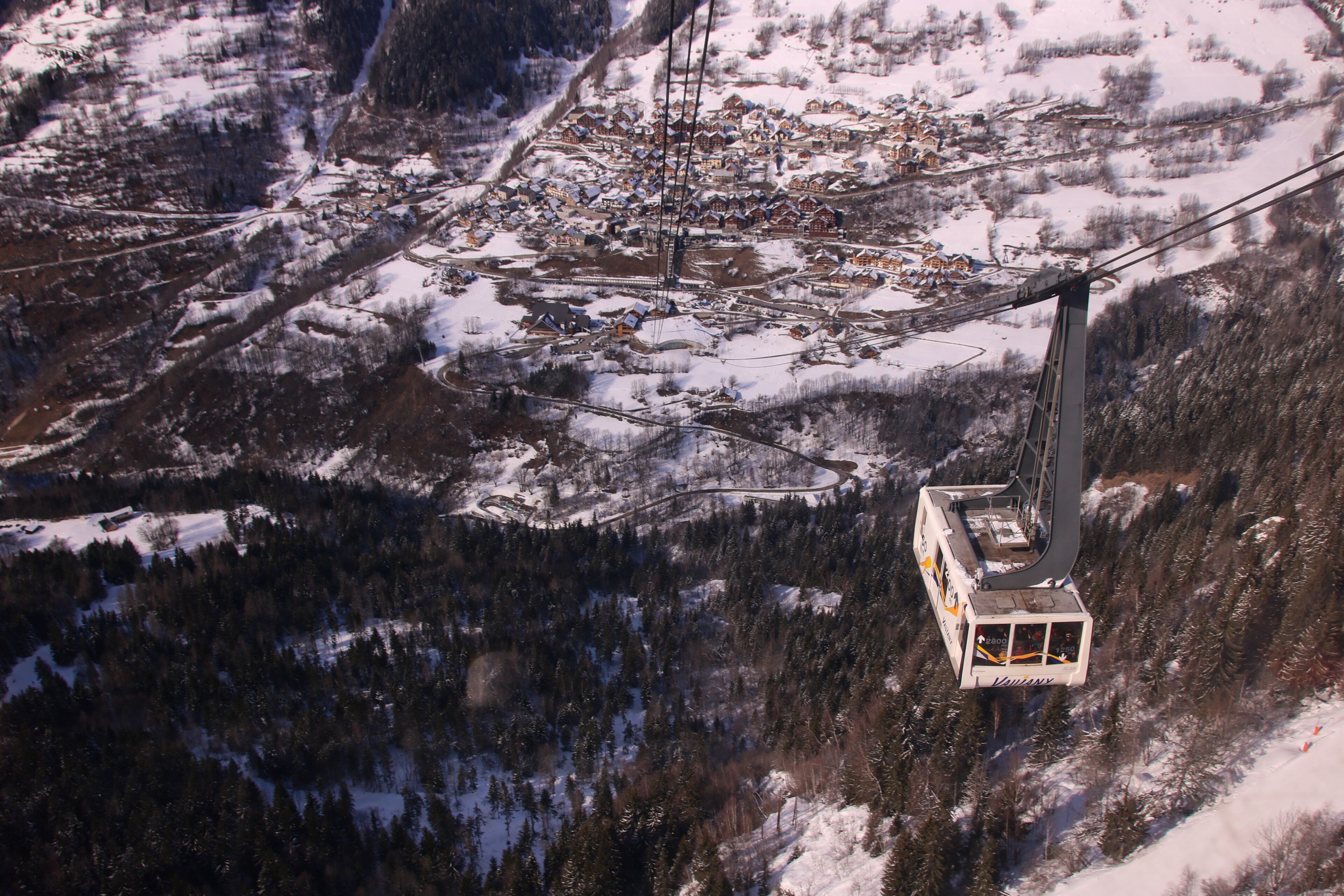 Un réseau de téléphériques dans une région montagneuse enneigée, avec un village situé en contrebas.