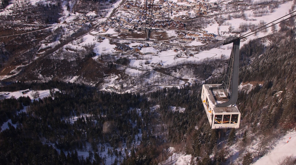 Un réseau de téléphériques dans une région montagneuse enneigée, avec un village situé en contrebas.