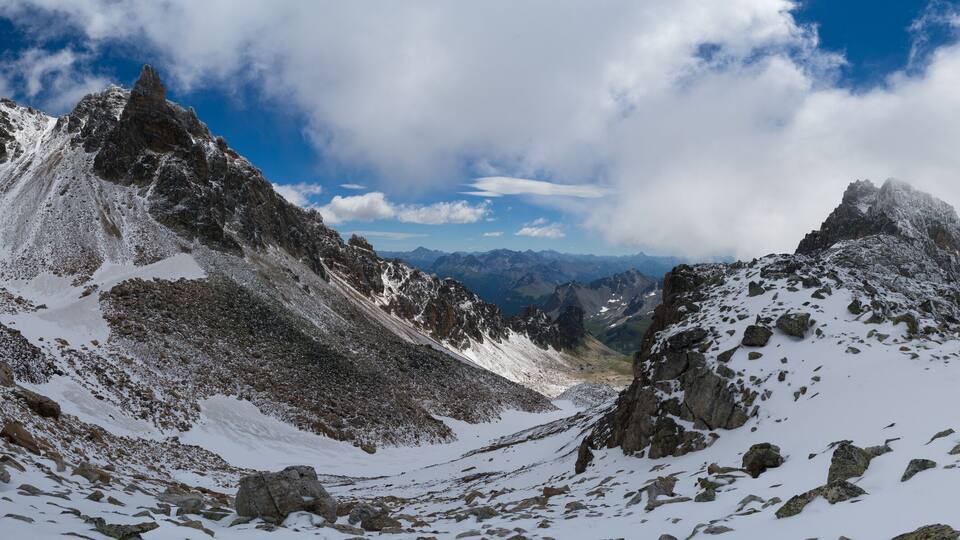 A snow-covered mountain range with sharp peaks and rocky terrain.