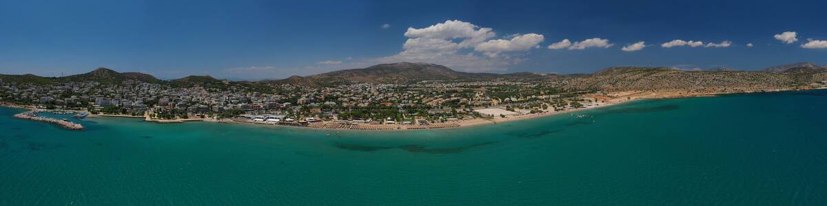Aerial drone photo of famous seaside village of Varkiza with deep turquoise sandy beaches and clear blue sky, Athens riviera, Attica, Greece