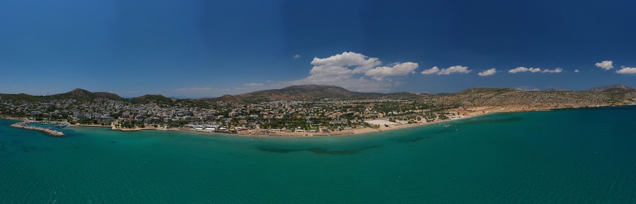 Aerial drone photo of famous seaside village of Varkiza with deep turquoise sandy beaches and clear blue sky, Athens riviera, Attica, Greece