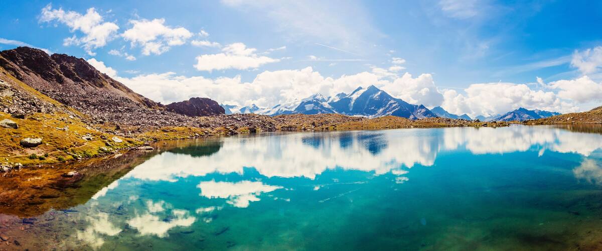A mountain lake with clear water reflecting the sky and mountains.
