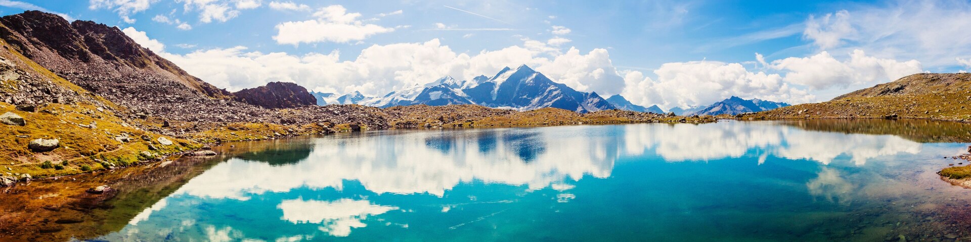 A mountain lake with clear water reflecting the sky and mountains.