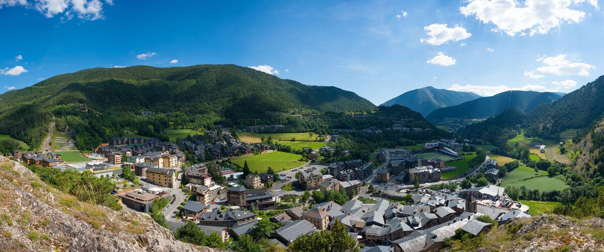 A mountainous town with buildings nestled in valleys, surrounded by lush greenery and hills.