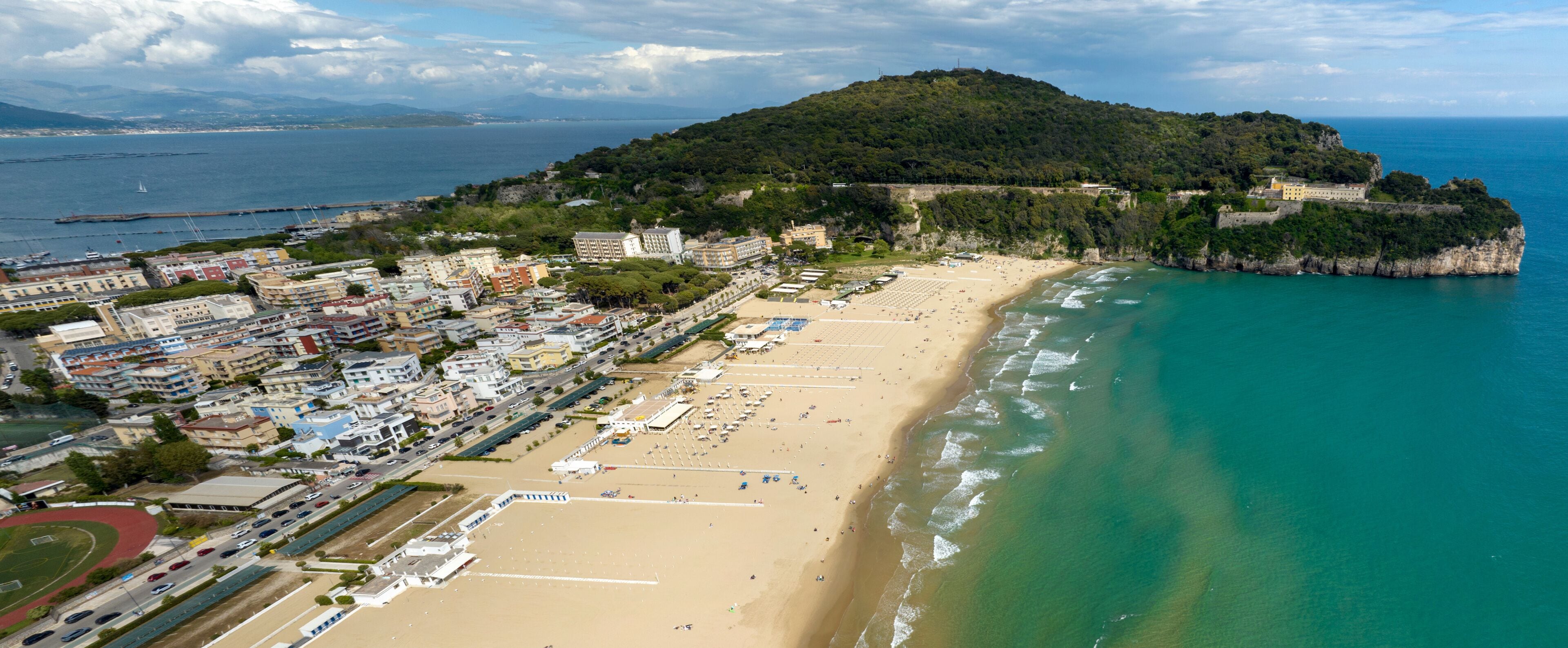 Aerial view of Serapo beach overlooking the Mediterranean Sea. It is the main beach of Gaeta, in the province of Latina, Lazio, Italy. In the background is the Monte Orlando regional park.