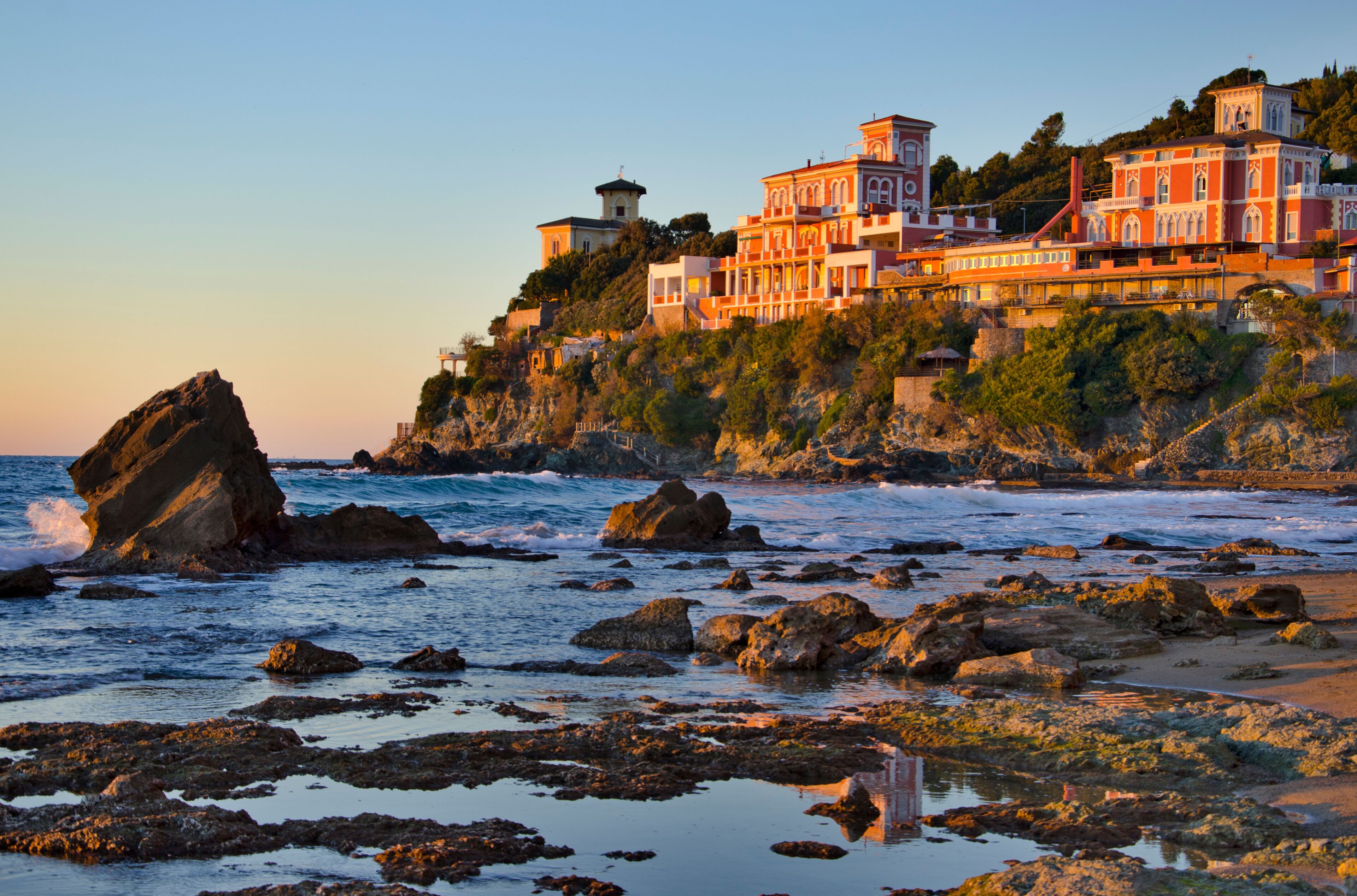 A coastal town with a prominent building complex on a cliff overlooking the sea.