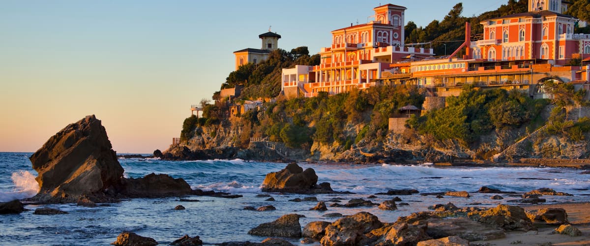 A coastal town with a prominent building complex on a cliff overlooking the sea.