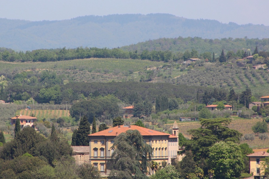 Un paysage rural caractérisé par des collines douces, des vignobles et des bâtiments traditionnels aux toits de tuiles rouges.