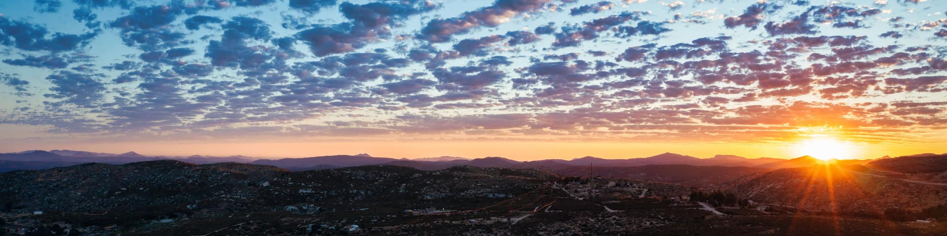 Beautiful sunset with popcorn clouds in San Diego East County with mountain views.