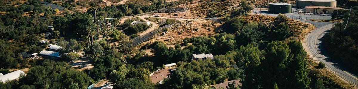 Un paysage montagneux avec une route sinueuse, un grand bâtiment et de vastes zones boisées.