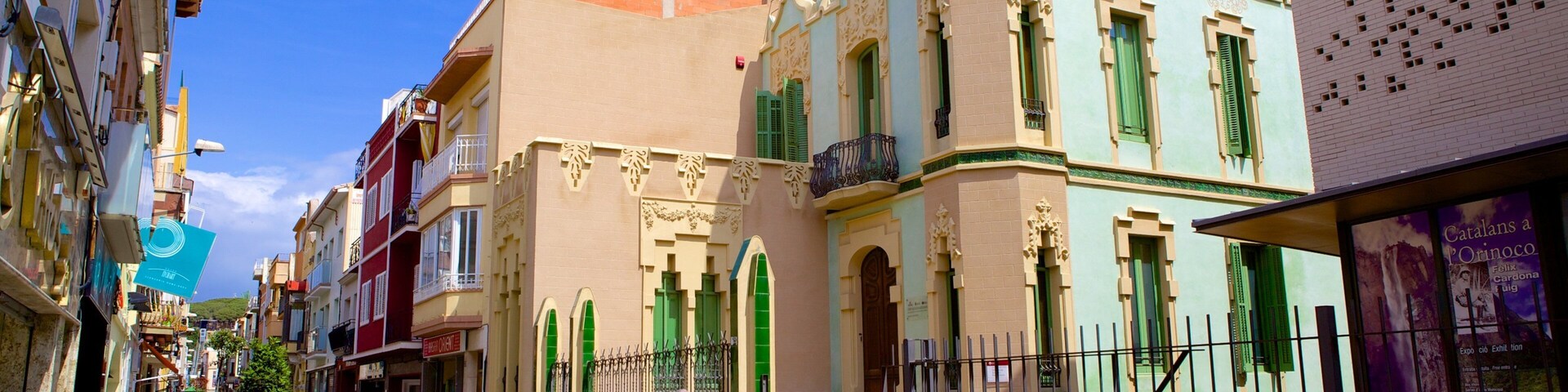 A street with historic buildings, a person in a red jacket, and a fence.