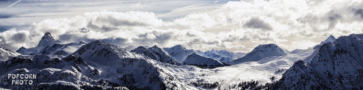 Une chaîne de montagnes enneigée sous un ciel partiellement nuageux.