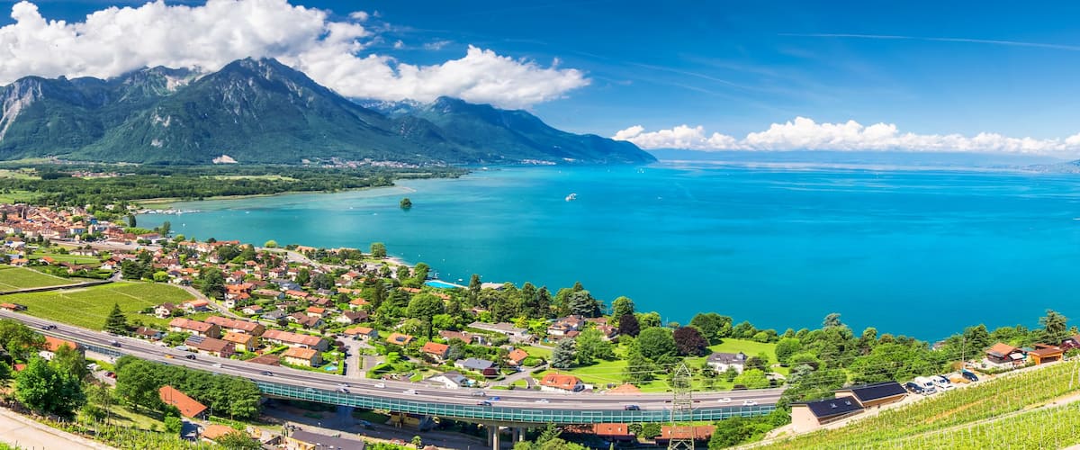 A coastal town with a mountain backdrop, vineyards, and a bridge.