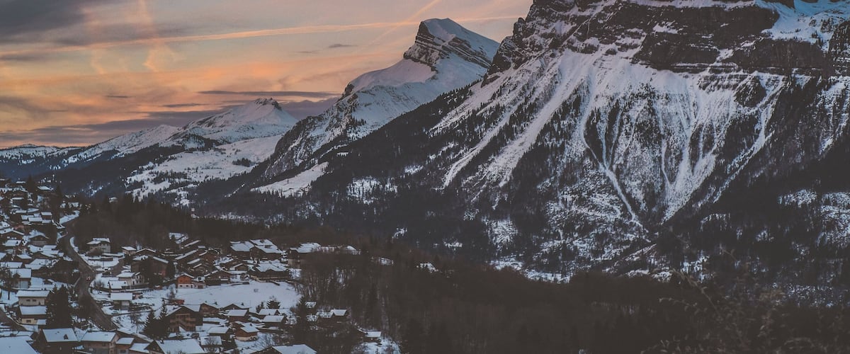 A snow-covered mountain range with a small village at its base.